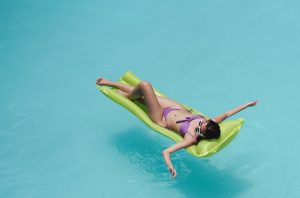 Jeune femme dans sa piscine sur un matelas gonflable